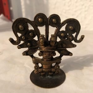 INDIGENA SOSTENIENDO CON DOS MANOS ARBOL DE BOLAS